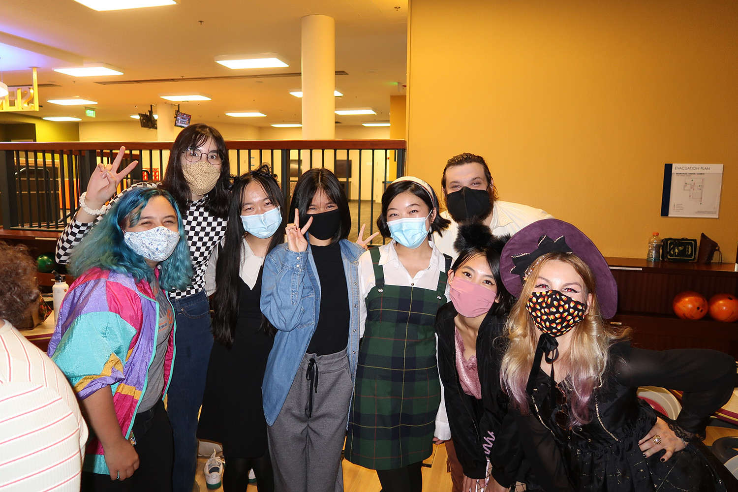 Group of students smiling and wearing halloween costumes in the UCD Game Room.